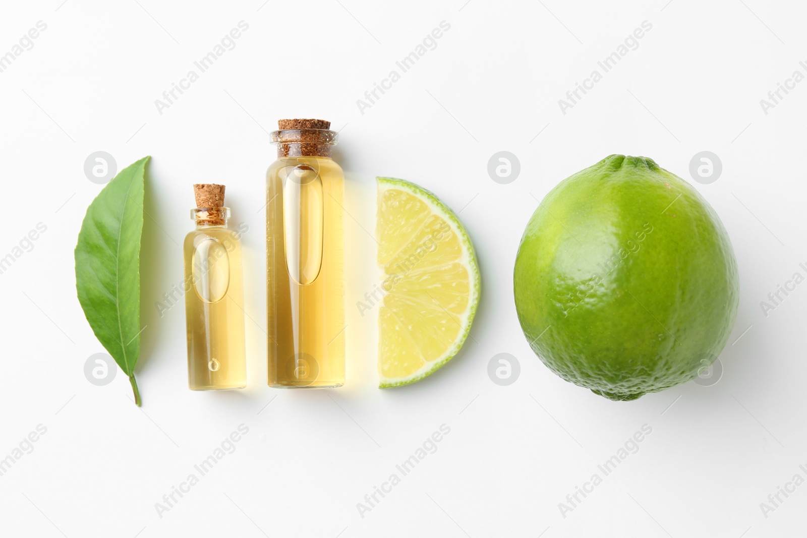 Photo of Bottles of essential oils, lime and green leaf on white background, flat lay