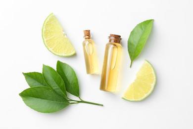 Photo of Bottles of essential oils, lime and green leaves on white background, flat lay