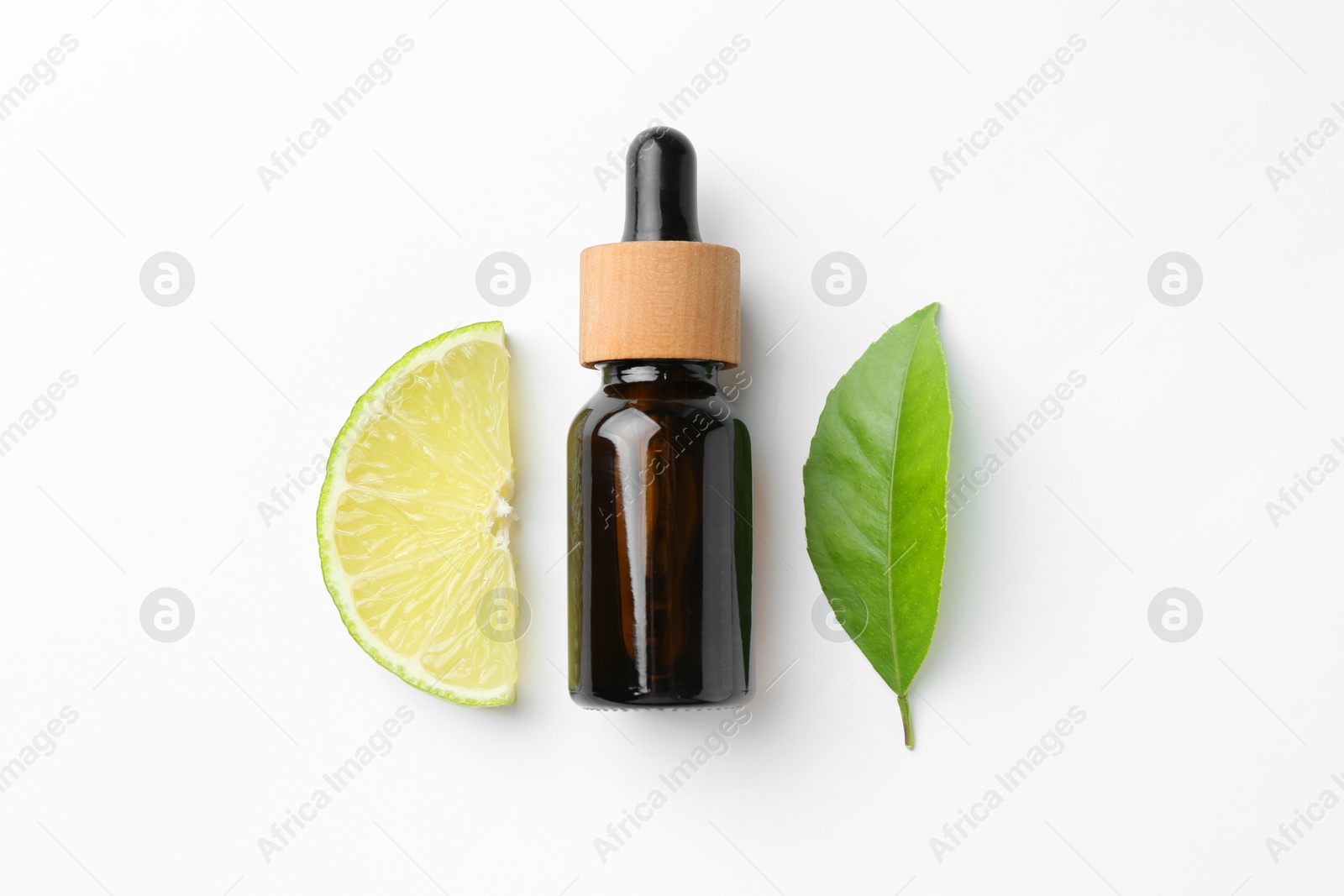 Photo of Bottle of essential oil, lime and green leaf on white background, flat lay