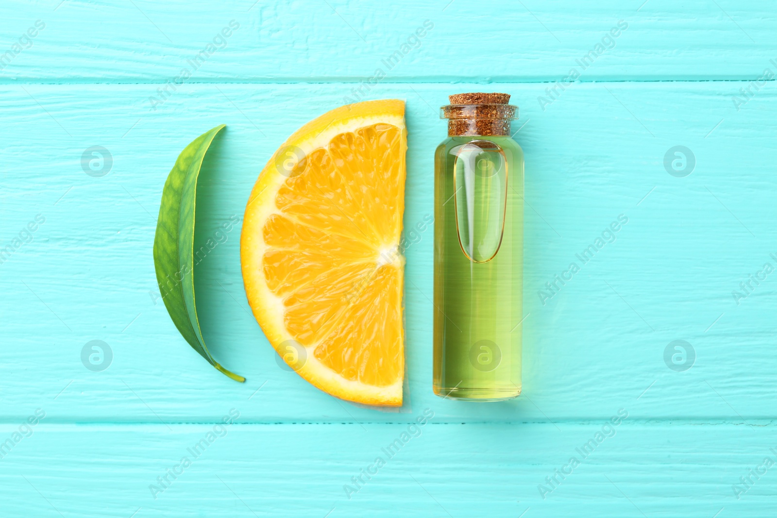 Photo of Bottle of essential oil, orange and green leaf on turquoise wooden table, flat lay