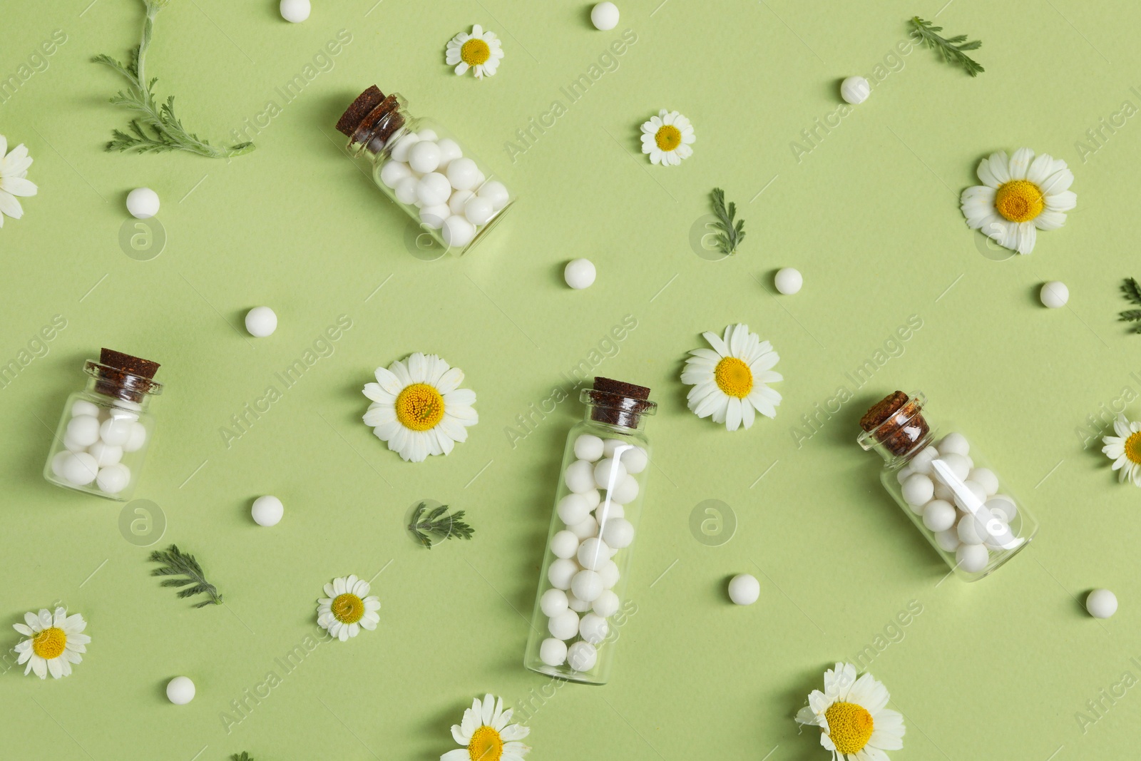 Photo of Flat lay composition with homeopathic remedy and chamomiles on light green background