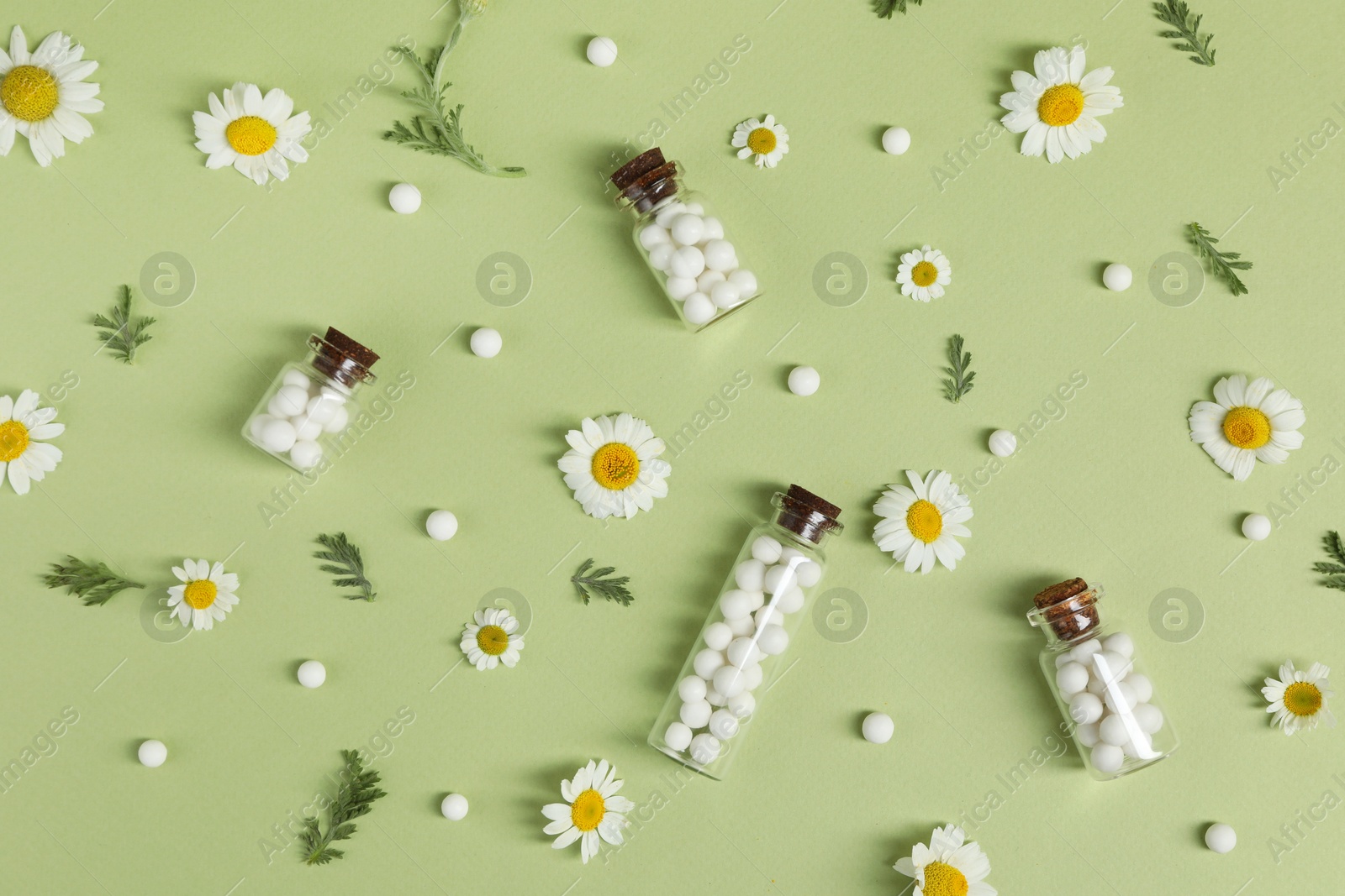 Photo of Flat lay composition with homeopathic remedy and chamomiles on light green background