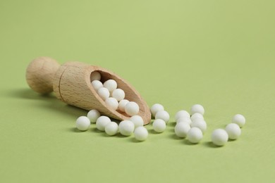 Photo of Scoop with homeopathic remedy on light green background