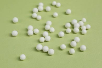 Photo of Homeopathic remedy on light green background. Alternative medicine