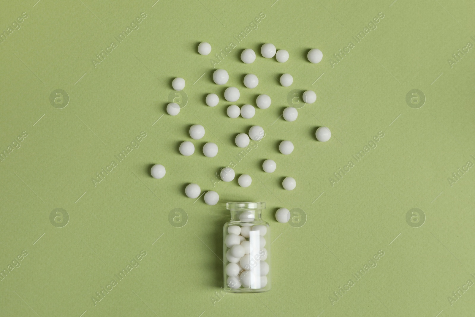 Photo of Bottle of homeopathic remedy on light green background, flat lay