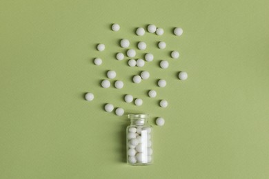 Photo of Bottle of homeopathic remedy on light green background, flat lay