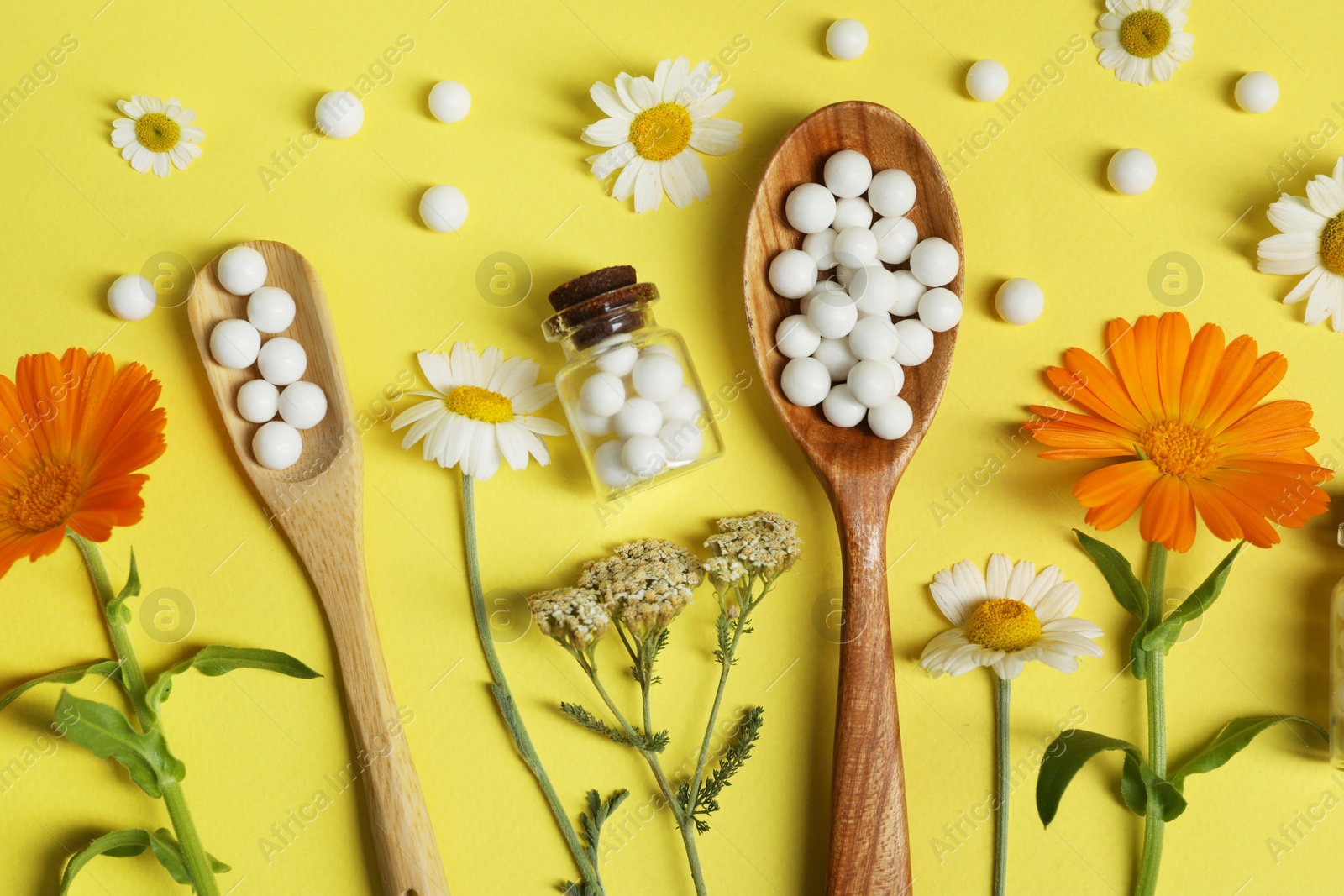 Photo of Flat lay composition with homeopathic remedy and flowers on yellow background