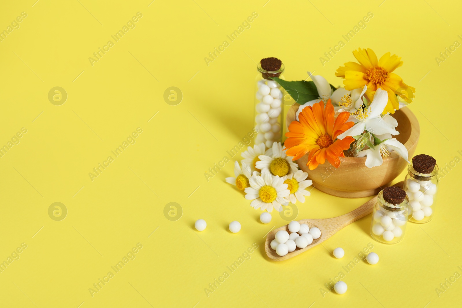 Photo of Homeopathic remedy and flowers on yellow background. Space for text