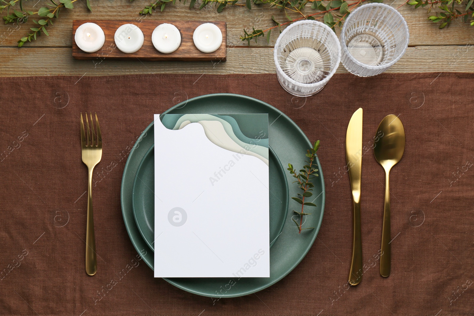 Photo of Empty menu, plates, cutlery, glasses and decor on wooden table, top view. Mockup for design