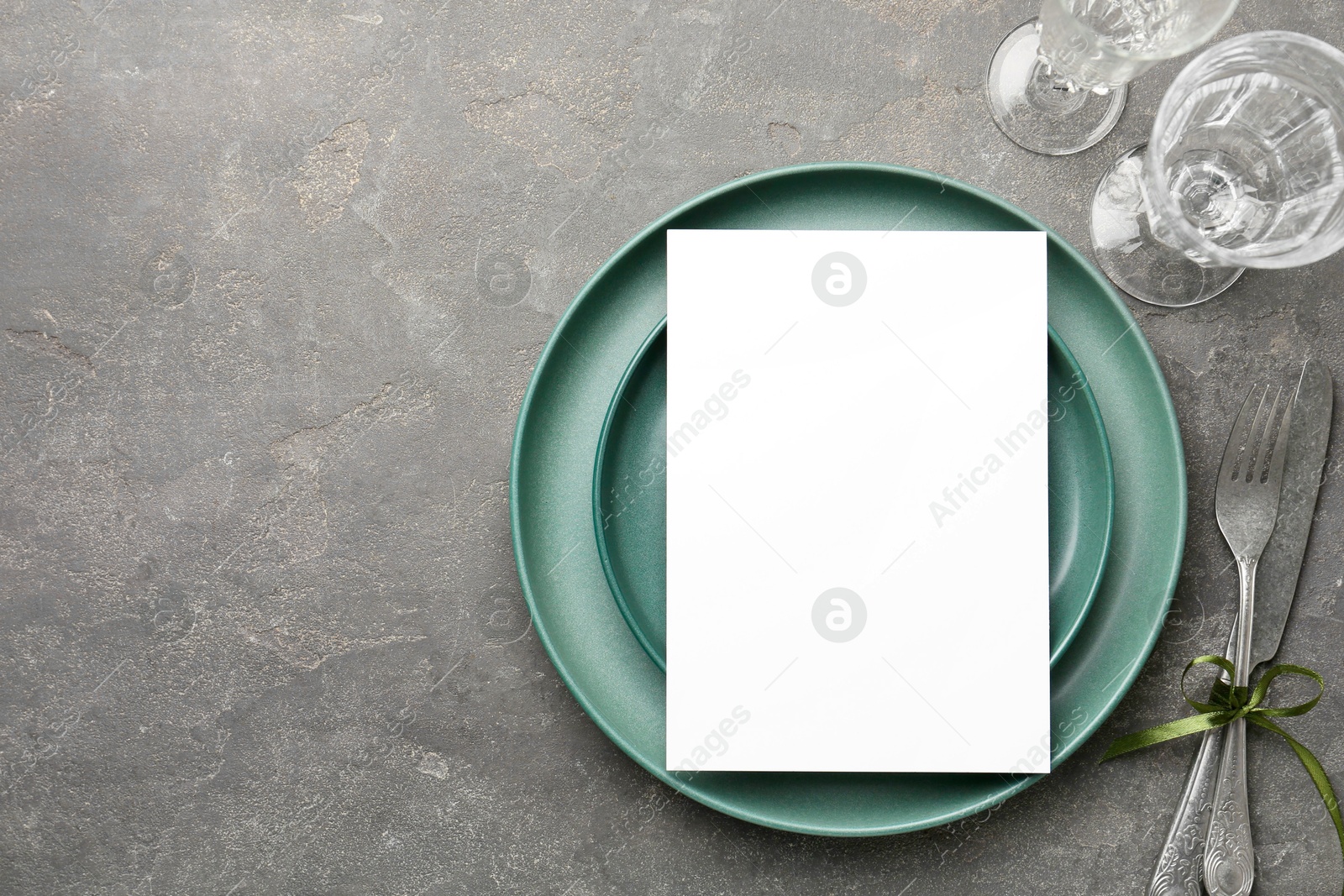 Photo of Empty menu, plates, cutlery and glasses on grey table, top view. Mockup for design