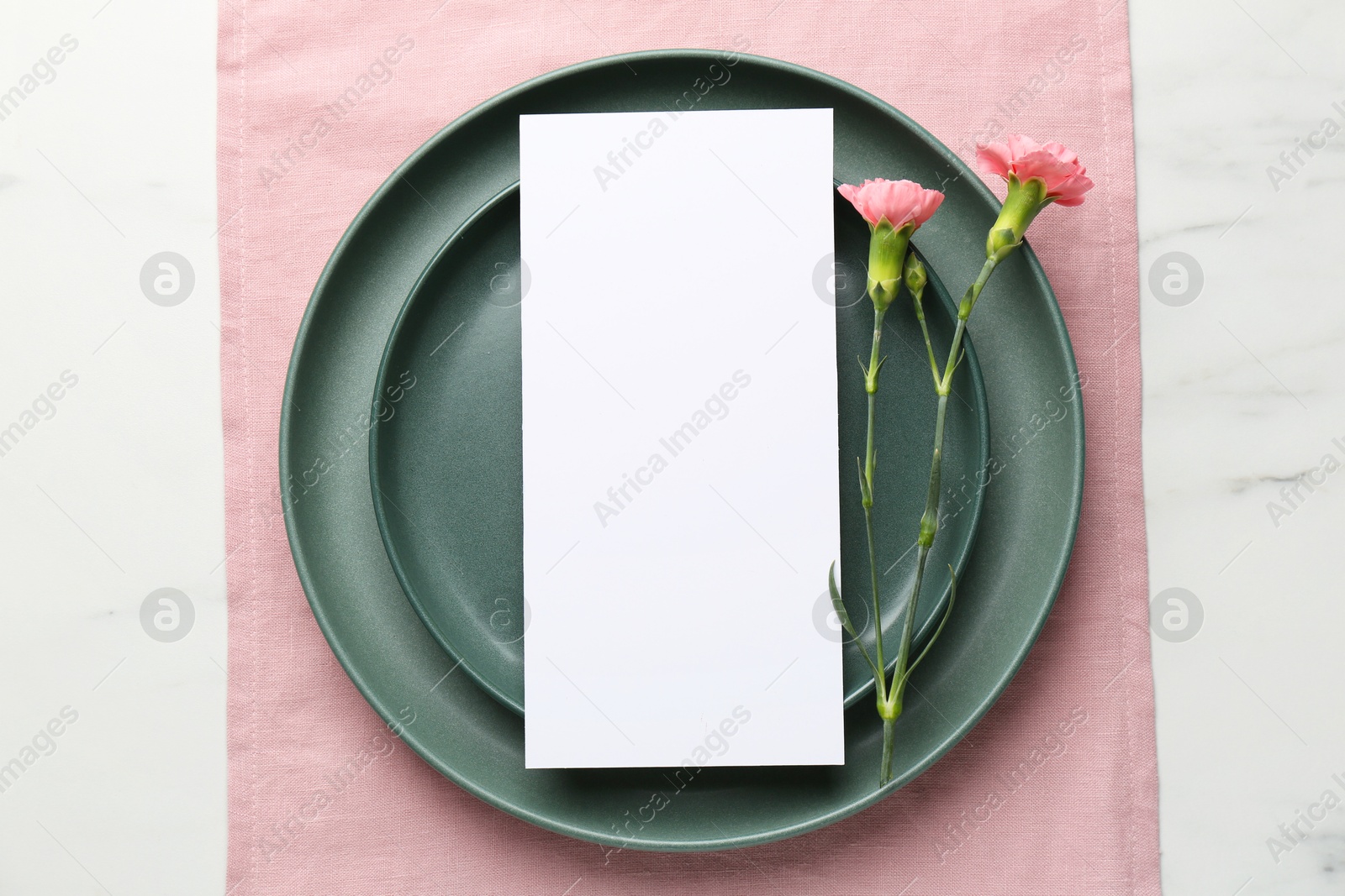 Photo of Empty menu, plates and floral decor on white marble table, top view. Mockup for design