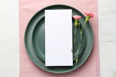 Photo of Empty menu, plates and floral decor on white marble table, top view. Mockup for design