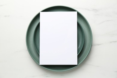 Photo of Empty menu and plates on white marble table, top view. Mockup for design