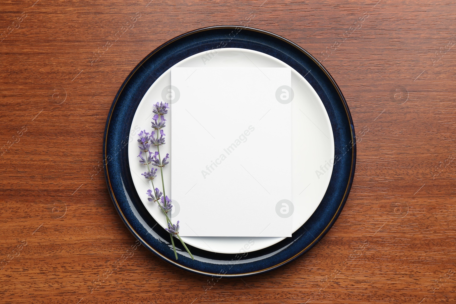 Photo of Empty menu, plates and floral decor on wooden table, top view. Mockup for design