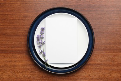 Empty menu, plates and floral decor on wooden table, top view. Mockup for design