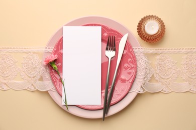 Photo of Empty menu, tableware, candle and floral decor on beige table, top view. Mockup for design