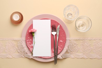 Photo of Empty menu, tableware, candle and floral decor on beige table, top view. Mockup for design