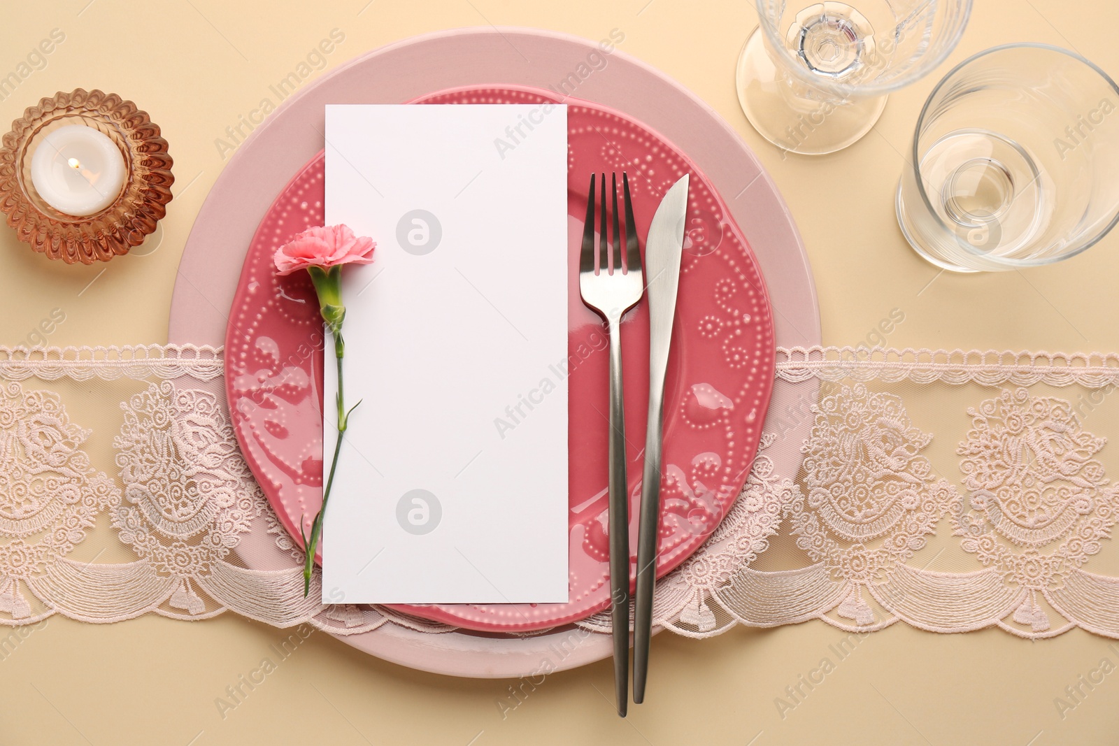 Photo of Empty menu, tableware, candle and floral decor on beige table, top view. Mockup for design