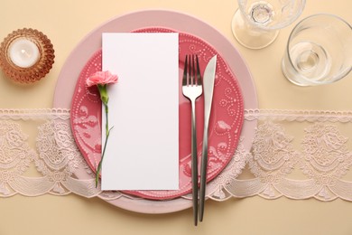 Photo of Empty menu, tableware, candle and floral decor on beige table, top view. Mockup for design