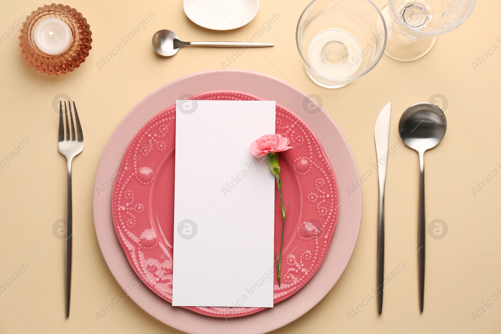 Photo of Empty menu, tableware, candle and floral decor on beige table, flat lay. Mockup for design