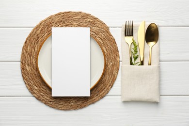 Photo of Empty menu, plate, cutlery, napkin and floral decor on white wooden table, top view. Mockup for design