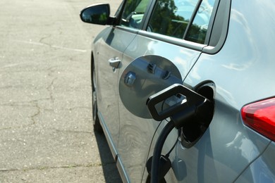 Photo of Charging modern electric car from station outdoors, space for text