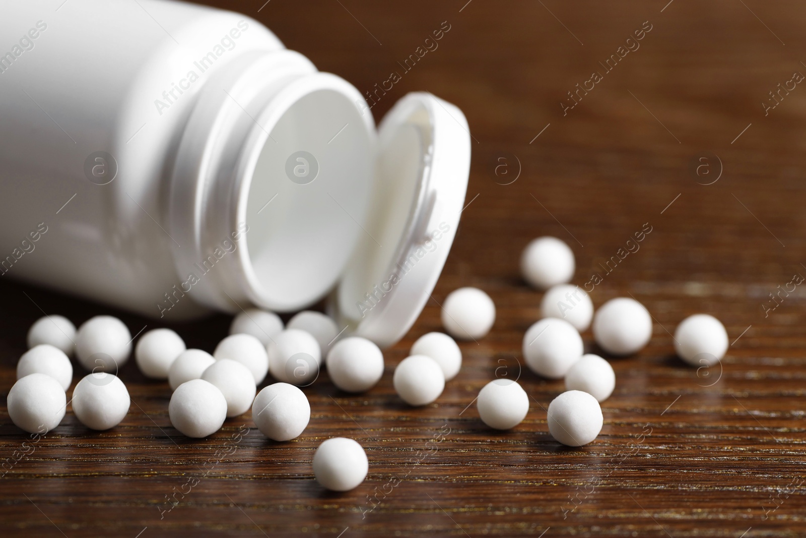 Photo of Homeopathy. Plastic bottle with pills on wooden table, closeup