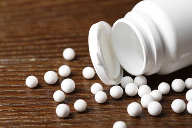 Photo of Homeopathy. Plastic bottle with pills on wooden table, closeup