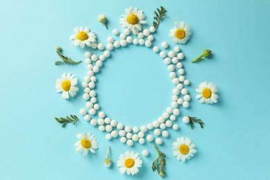 Photo of Homeopathy. Frame made of pills and chamomile flowers on light blue background, top view. Space for text