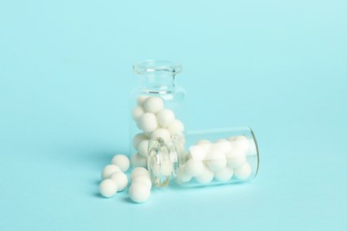 Photo of Homeopathy. Glass bottles with pills on light blue background