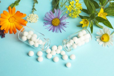 Photo of Homeopathy. Glass bottles with pills and different meadow flowers on light blue background