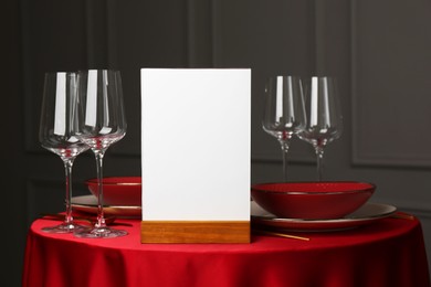 Photo of Menu holder, clean dishware and cutlery on red table in restaurant