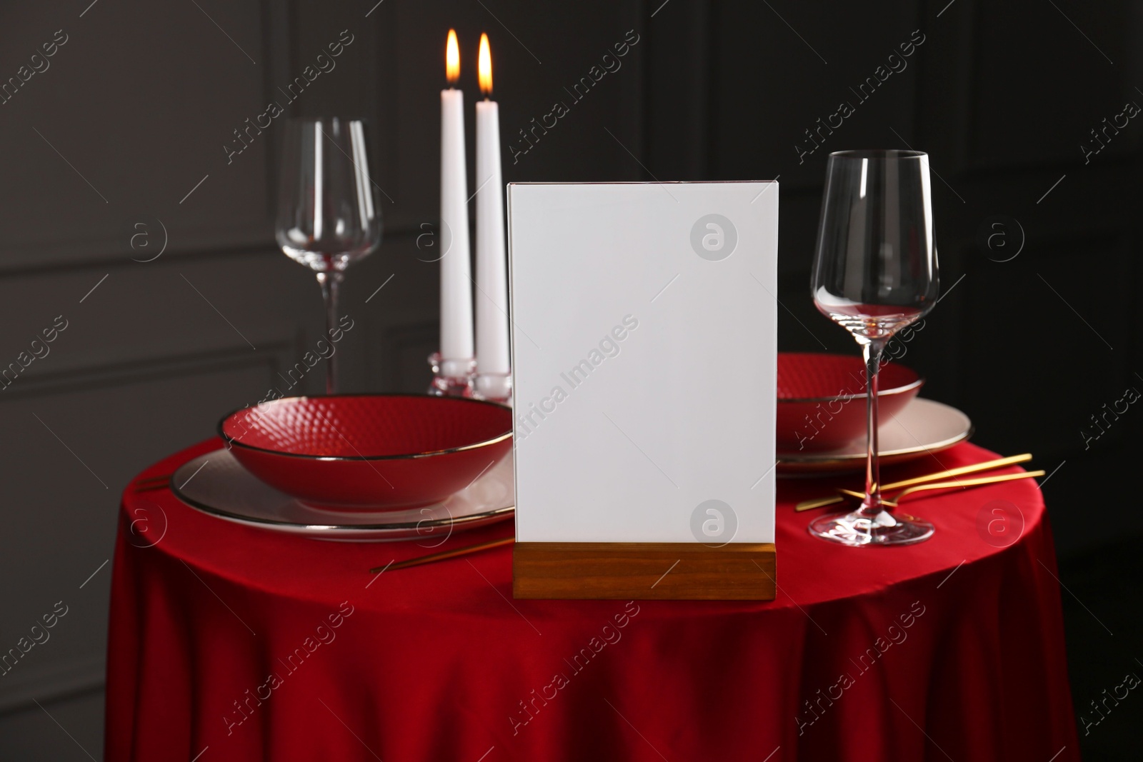 Photo of Menu holder, clean dishware and cutlery on red table in restaurant