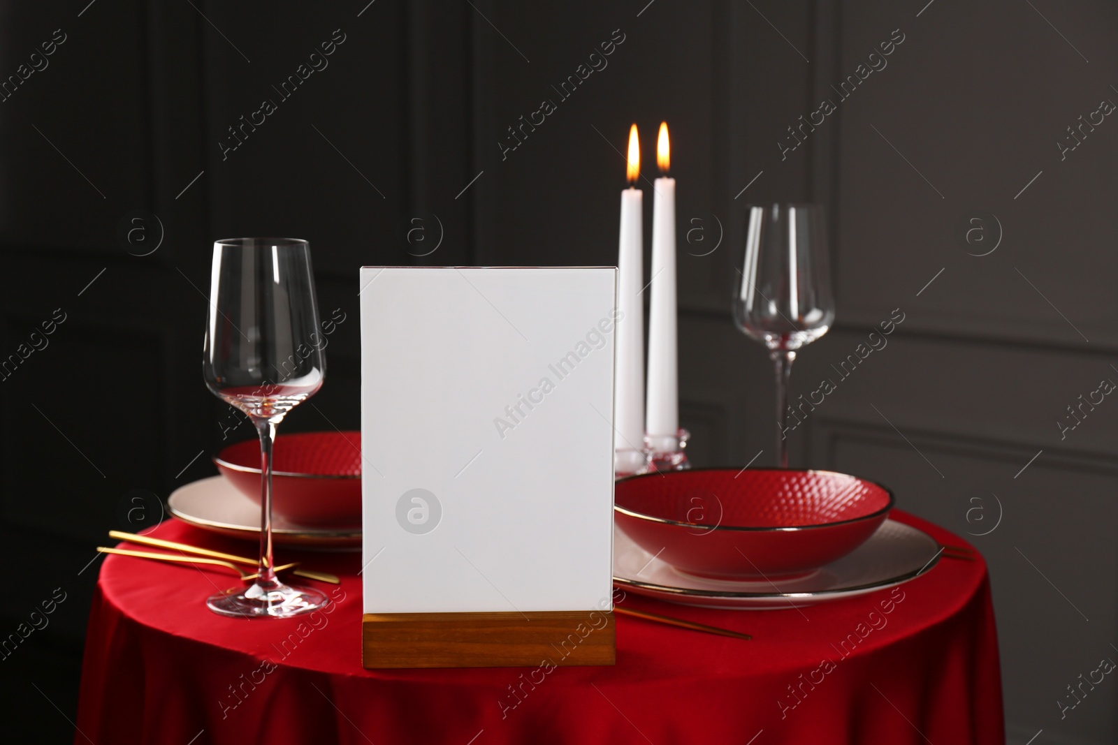 Photo of Menu holder, clean dishware and cutlery on red table in restaurant