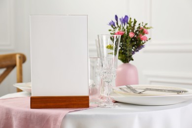 Photo of Menu holder, clean dishware and vase with beautiful flowers on white table in restaurant