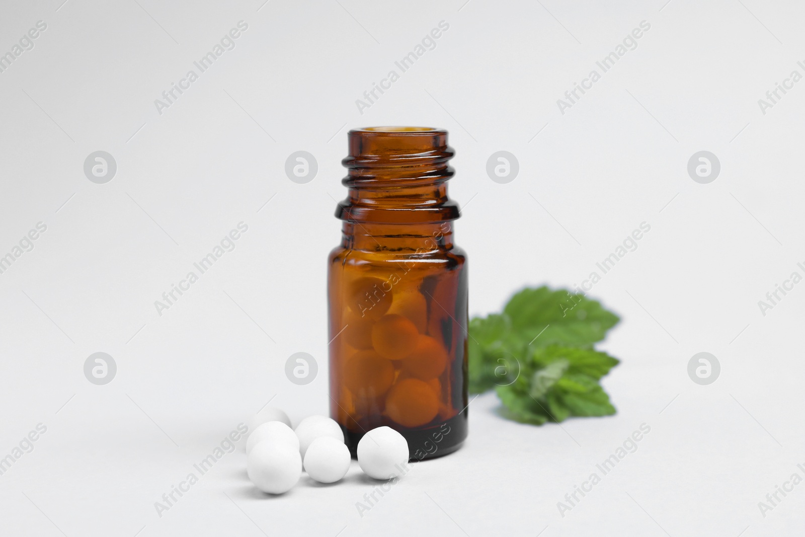 Photo of Homeopathy. Glass bottle, pills and mint on white background