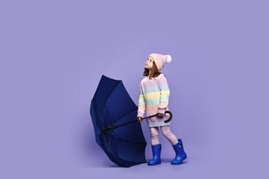 Photo of Cute little girl with blue umbrella on purple background