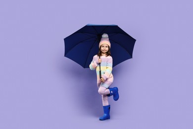 Photo of Cute little girl with blue umbrella on purple background