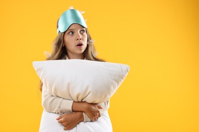 Photo of Overslept girl with sleep mask and pillow on orange background, space for text