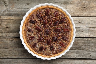 Delicious pecan pie in baking dish on wooden table, top view