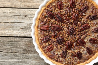 Photo of Delicious pecan pie in baking dish on wooden table, top view