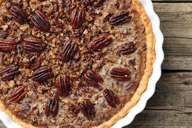 Photo of Delicious pecan pie in baking dish on wooden table, top view