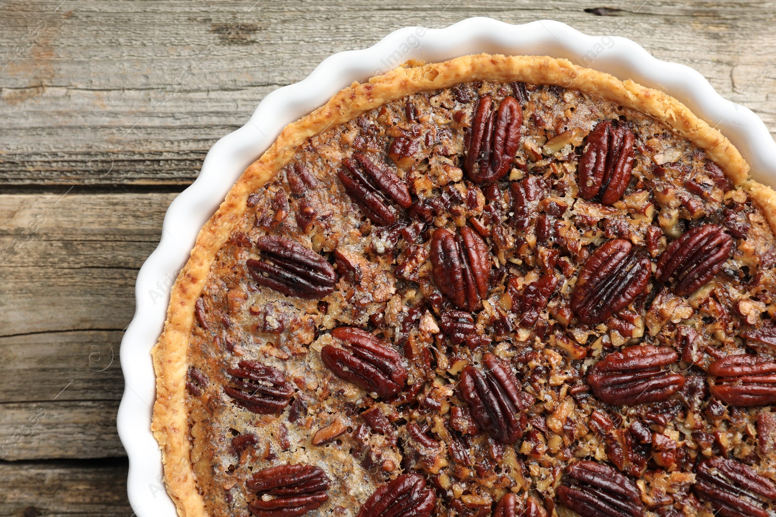 Photo of Delicious pecan pie in baking dish on wooden table, top view