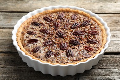 Delicious pecan pie in baking dish on wooden table, closeup