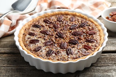 Delicious pecan pie in baking dish on wooden table, closeup