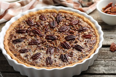 Delicious pecan pie in baking dish on wooden table, closeup