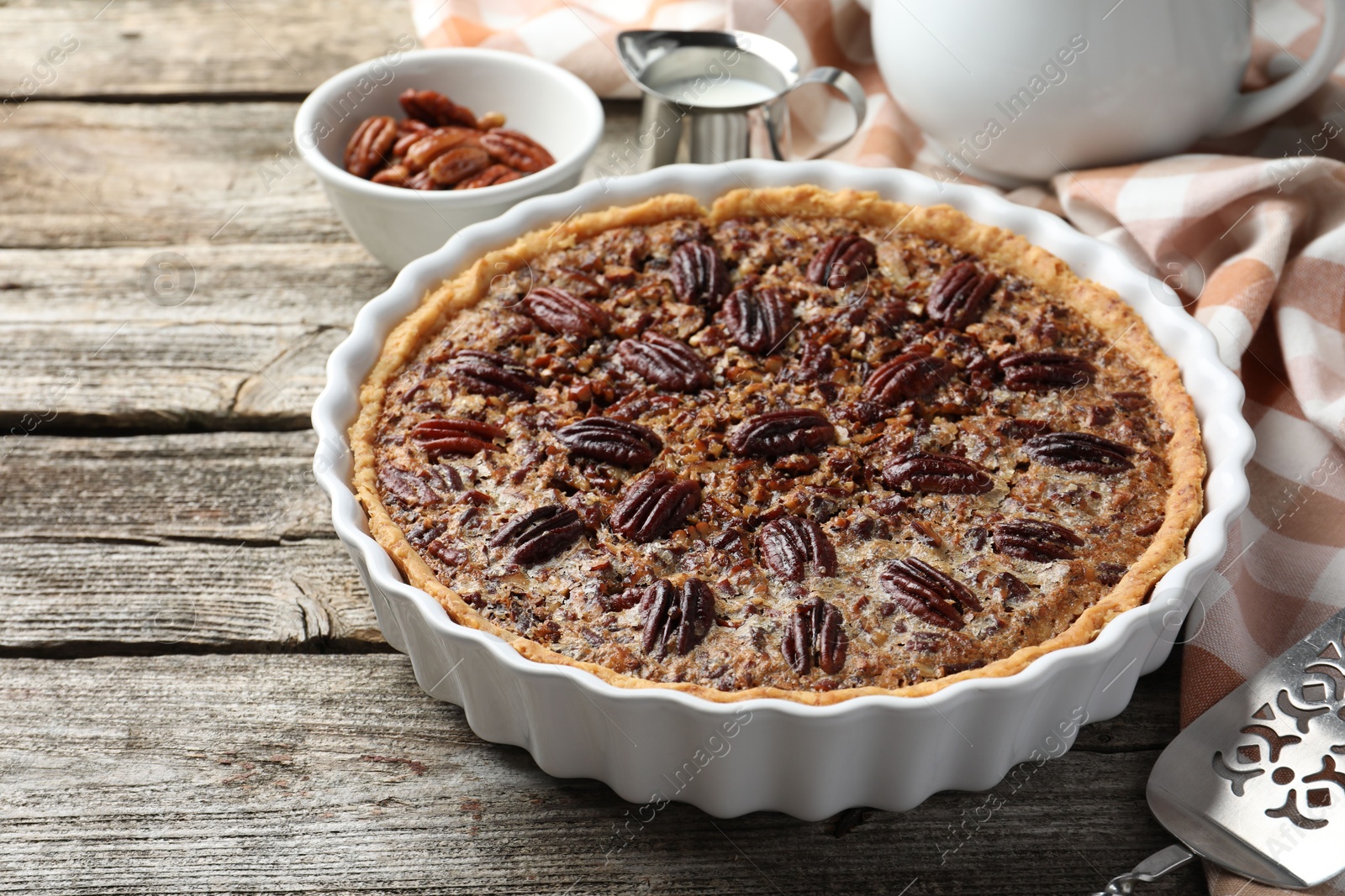 Photo of Delicious pecan pie in baking dish on wooden table, closeup