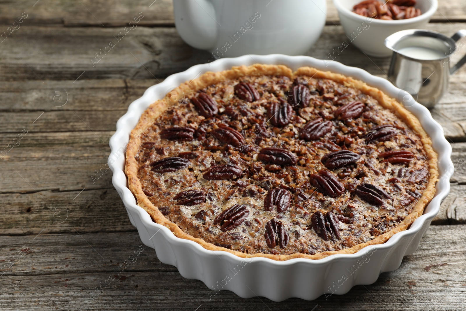 Photo of Delicious pecan pie in baking dish on wooden table, closeup