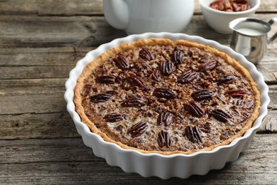 Delicious pecan pie in baking dish on wooden table, closeup