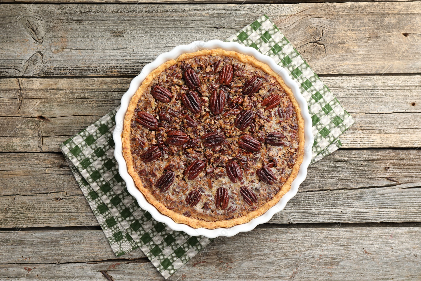 Photo of Delicious pecan pie in baking dish on wooden table, top view.